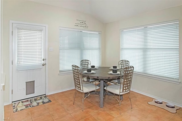 dining area featuring lofted ceiling, light tile patterned flooring, and baseboards