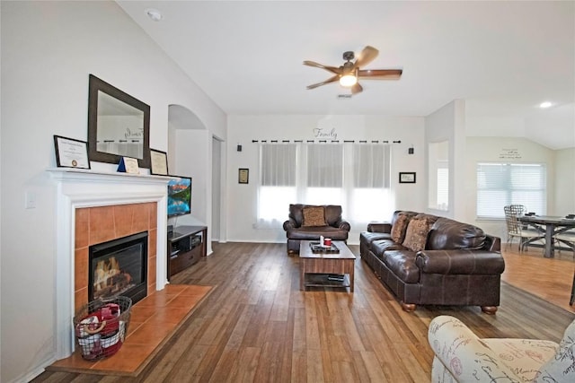 living room featuring a fireplace, wood finished floors, visible vents, a ceiling fan, and vaulted ceiling