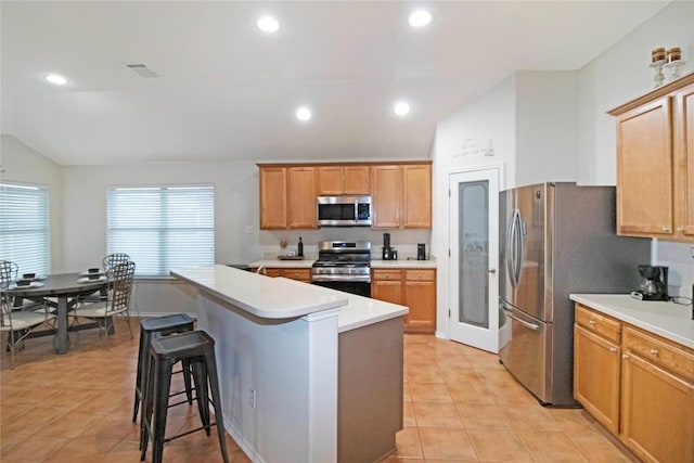 kitchen featuring a breakfast bar area, light tile patterned flooring, recessed lighting, vaulted ceiling, and appliances with stainless steel finishes