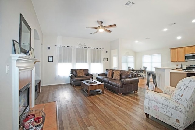 living room with a fireplace, recessed lighting, visible vents, vaulted ceiling, and light wood-type flooring