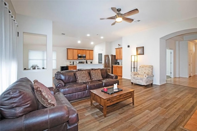 living area with visible vents, arched walkways, wood finished floors, and recessed lighting