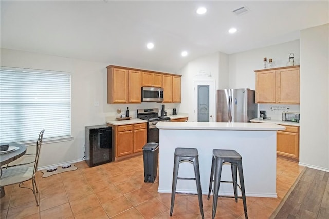 kitchen with beverage cooler, stainless steel appliances, light countertops, and a center island