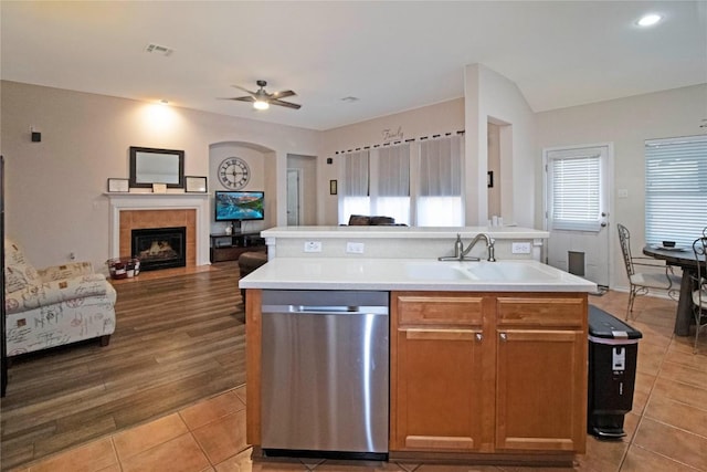 kitchen with tile patterned flooring, a sink, open floor plan, stainless steel dishwasher, and an island with sink