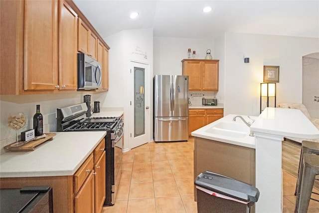 kitchen with recessed lighting, light countertops, appliances with stainless steel finishes, light tile patterned flooring, and a sink