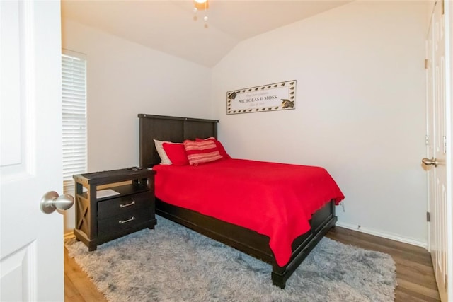 bedroom featuring lofted ceiling, baseboards, and wood finished floors