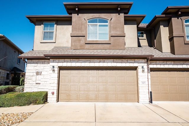 view of front of property featuring concrete driveway, roof with shingles, stucco siding, a garage, and stone siding