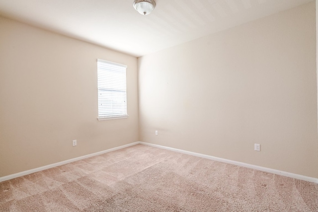 spare room featuring light carpet and baseboards