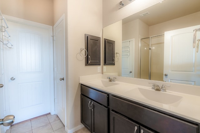 bathroom with tile patterned floors, a shower with shower door, visible vents, and a sink