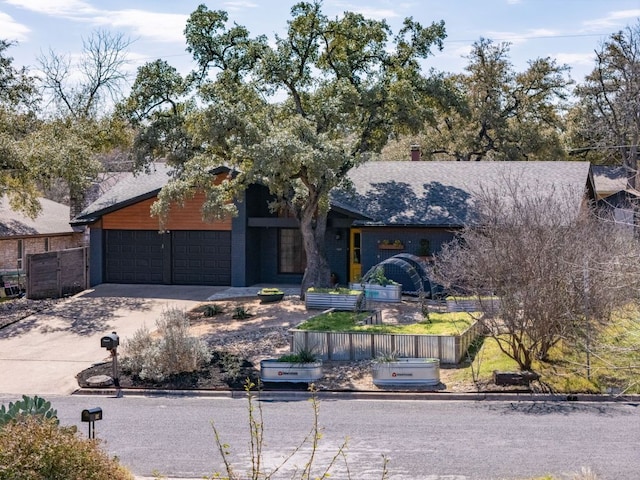 mid-century modern home featuring a garage, concrete driveway, and fence