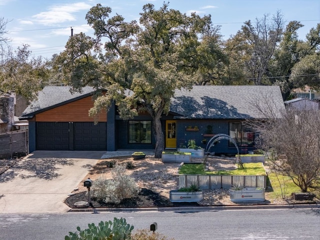 mid-century modern home with a shingled roof, driveway, and an attached garage