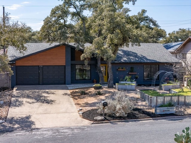 mid-century inspired home with a garage, driveway, brick siding, and fence