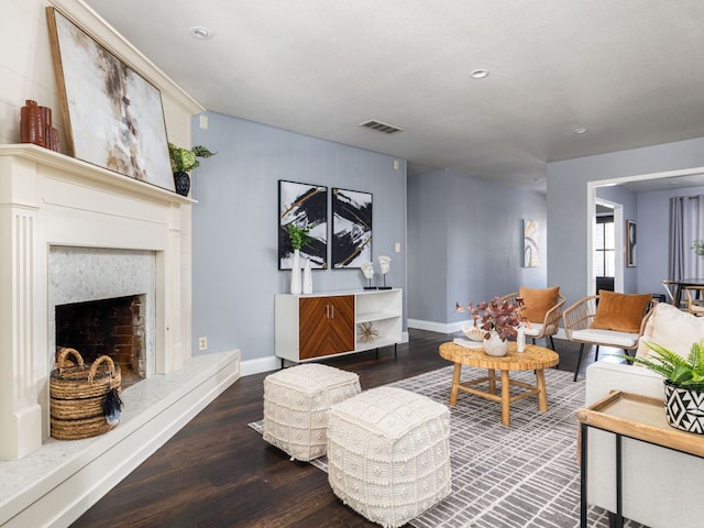 living room featuring baseboards, visible vents, wood finished floors, and a high end fireplace