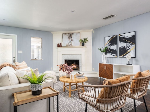 living area featuring visible vents, a fireplace with raised hearth, and wood finished floors