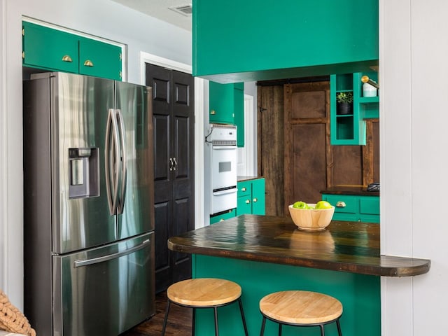 kitchen with oven, a breakfast bar, visible vents, stainless steel fridge with ice dispenser, and a warming drawer