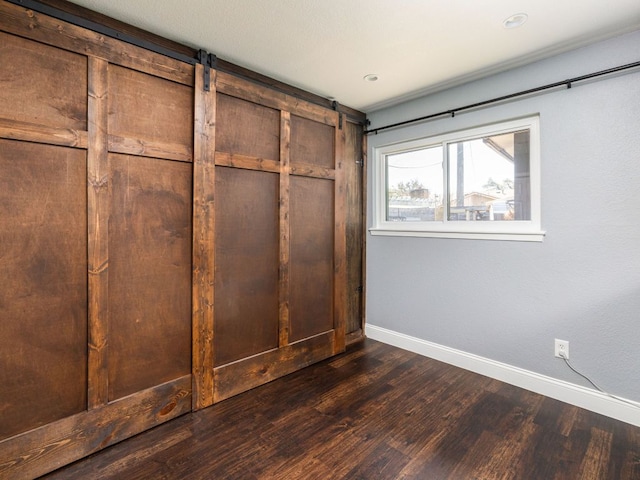 interior space with dark wood-style floors, a barn door, and baseboards