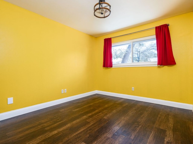 empty room with baseboards and dark wood-type flooring