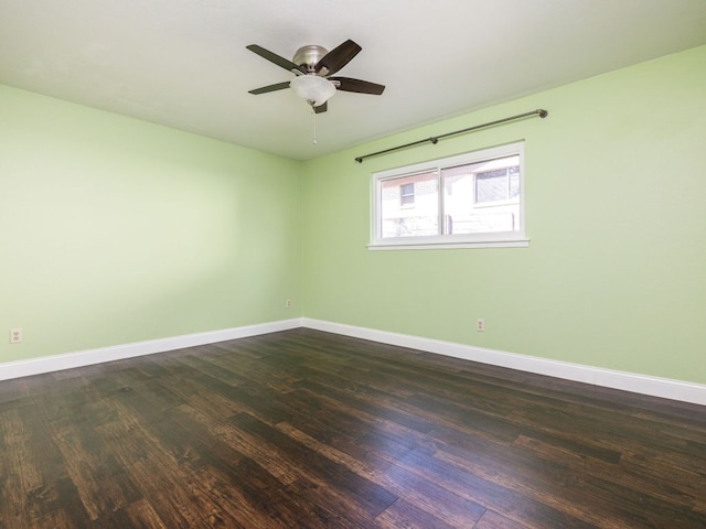 spare room featuring dark wood-style floors, ceiling fan, and baseboards