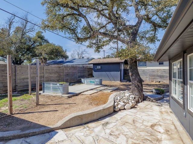 view of patio with a storage shed, a fenced backyard, and an outdoor structure