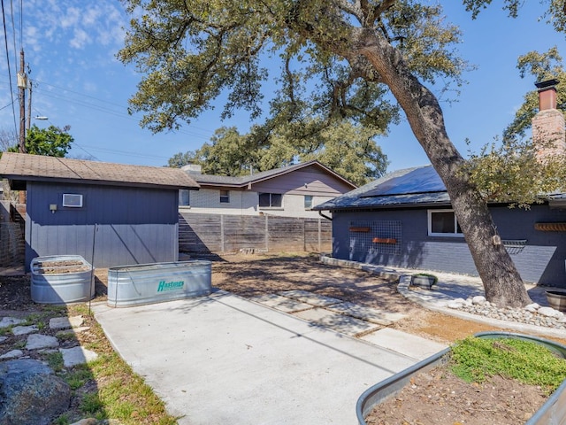 exterior space with solar panels, an outdoor structure, fence, a shed, and a patio area