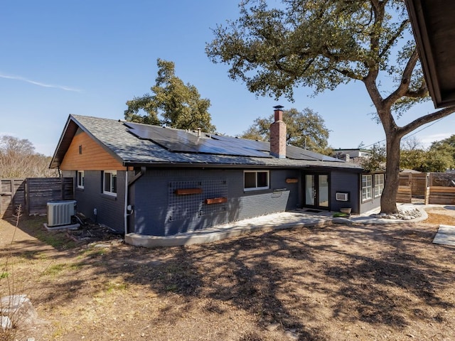 rear view of property with a fenced backyard, cooling unit, brick siding, french doors, and a chimney