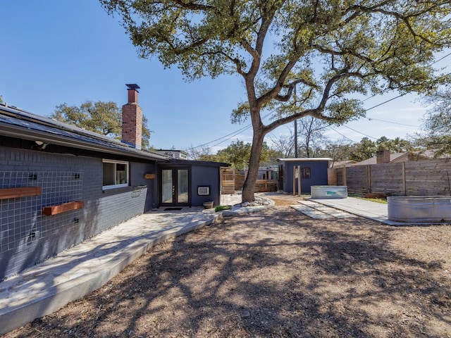 view of yard featuring an outbuilding, a patio, french doors, and a fenced backyard