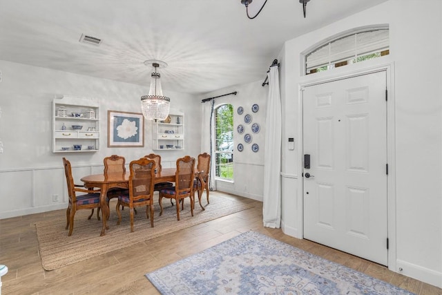 dining area featuring baseboards, visible vents, a chandelier, and wood finished floors