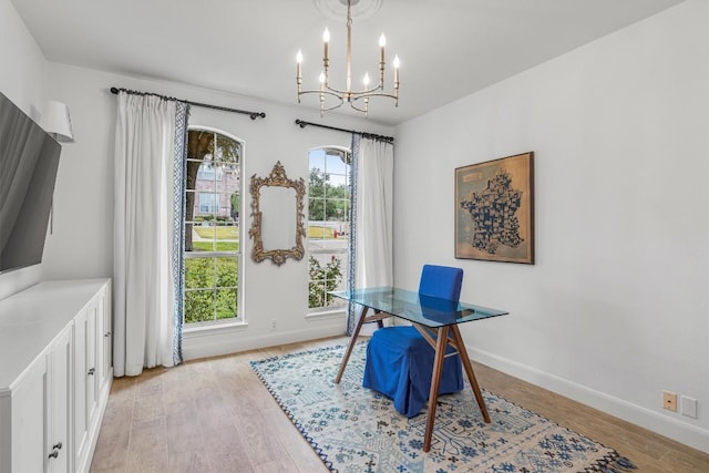 home office with light wood-type flooring, a wealth of natural light, and a notable chandelier