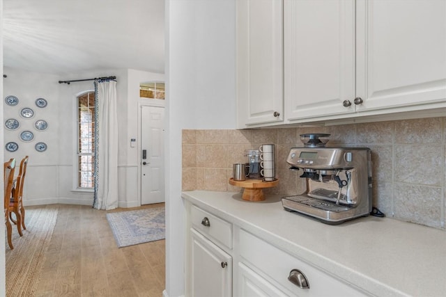 kitchen featuring light wood-style floors, light countertops, white cabinets, and decorative backsplash