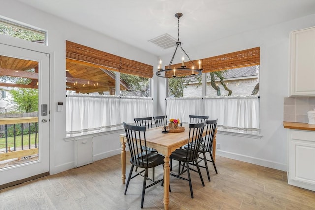 dining room with light wood finished floors, plenty of natural light, visible vents, and an inviting chandelier