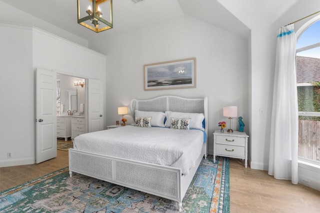 bedroom featuring ensuite bathroom, vaulted ceiling, wood finished floors, a chandelier, and baseboards