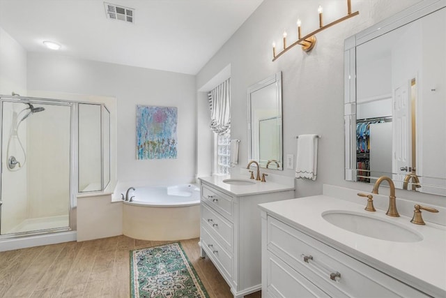 full bath with a stall shower, visible vents, a sink, and wood finished floors