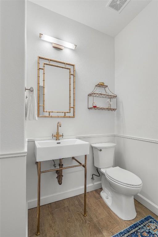 bathroom featuring toilet, baseboards, visible vents, and wood finished floors