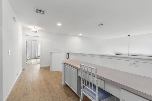 hallway featuring visible vents, light wood-style flooring, an upstairs landing, and recessed lighting