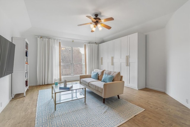 living room with a ceiling fan, light wood-style flooring, and baseboards