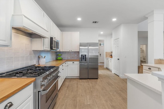 kitchen featuring custom range hood, visible vents, light wood-style flooring, appliances with stainless steel finishes, and white cabinetry