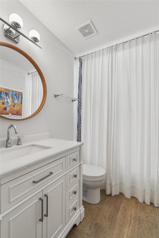 full bathroom featuring visible vents, vanity, toilet, and wood finished floors