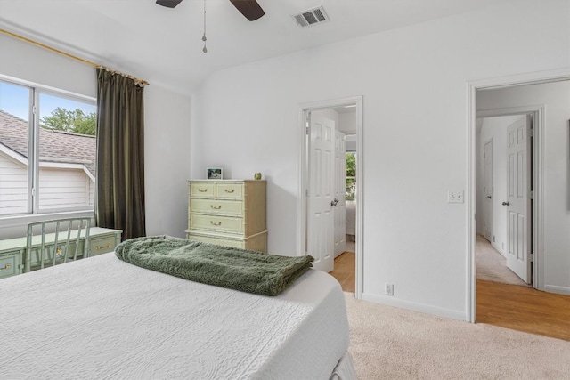 carpeted bedroom with vaulted ceiling, a ceiling fan, visible vents, and baseboards