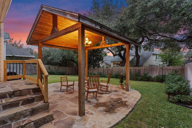 patio terrace at dusk with a yard, a gazebo, and a fenced backyard