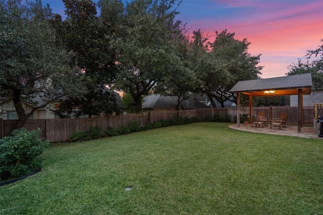 yard at dusk with a patio area and a fenced backyard