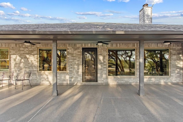 property entrance featuring roof with shingles, ceiling fan, and a chimney