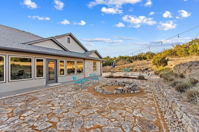 rear view of house with a shingled roof and a patio area