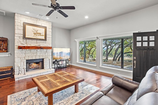 living area featuring visible vents, a stone fireplace, and hardwood / wood-style floors