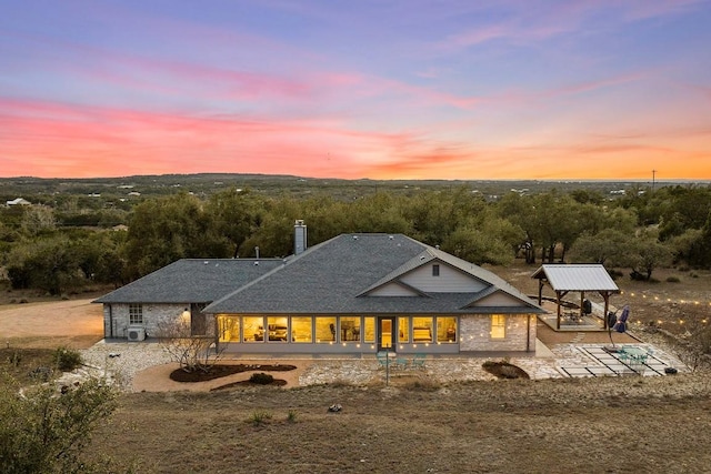 back of house at dusk with a patio, a chimney, and a gazebo