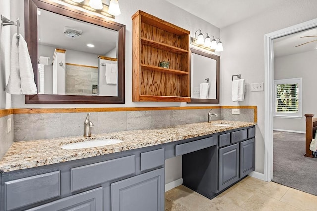 bathroom featuring tiled shower, a sink, decorative backsplash, and double vanity