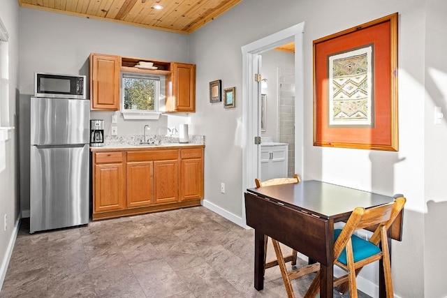 kitchen featuring baseboards, wooden ceiling, appliances with stainless steel finishes, light countertops, and a sink