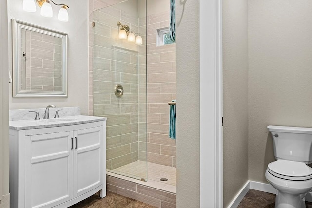 bathroom with tiled shower, vanity, toilet, and baseboards