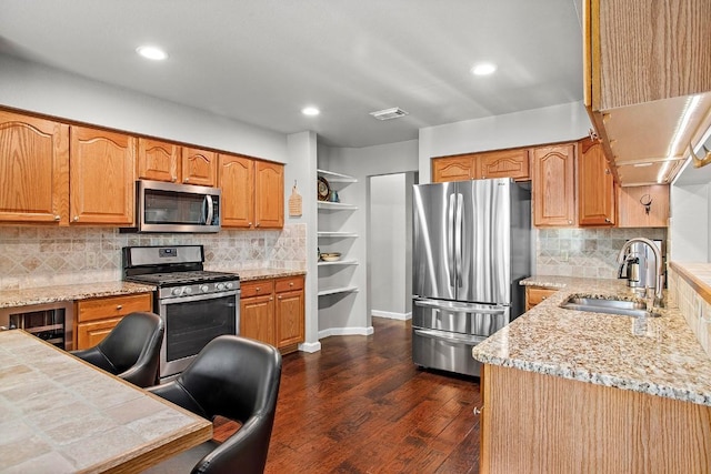 kitchen with visible vents, dark wood finished floors, appliances with stainless steel finishes, a sink, and backsplash