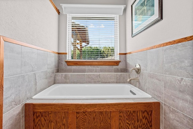 full bath featuring a garden tub and tile walls