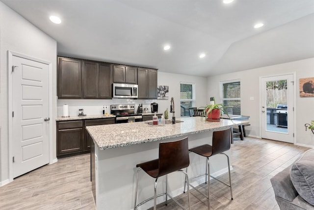 20602 Falcon, Lago Vista, TX 78645 - kitchen featuring stainless steel appliances, dark brown cabinets, a kitchen bar, vaulted ceiling, and light wood-style flooring