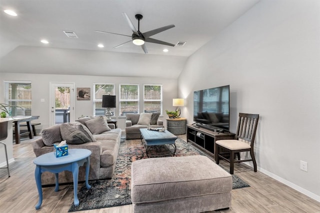 living area featuring vaulted ceiling, light wood-style flooring, visible vents, and a healthy amount of sunlight